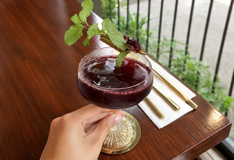 Melati Drinks cocktail with a fresh mint garnish served at a table.
