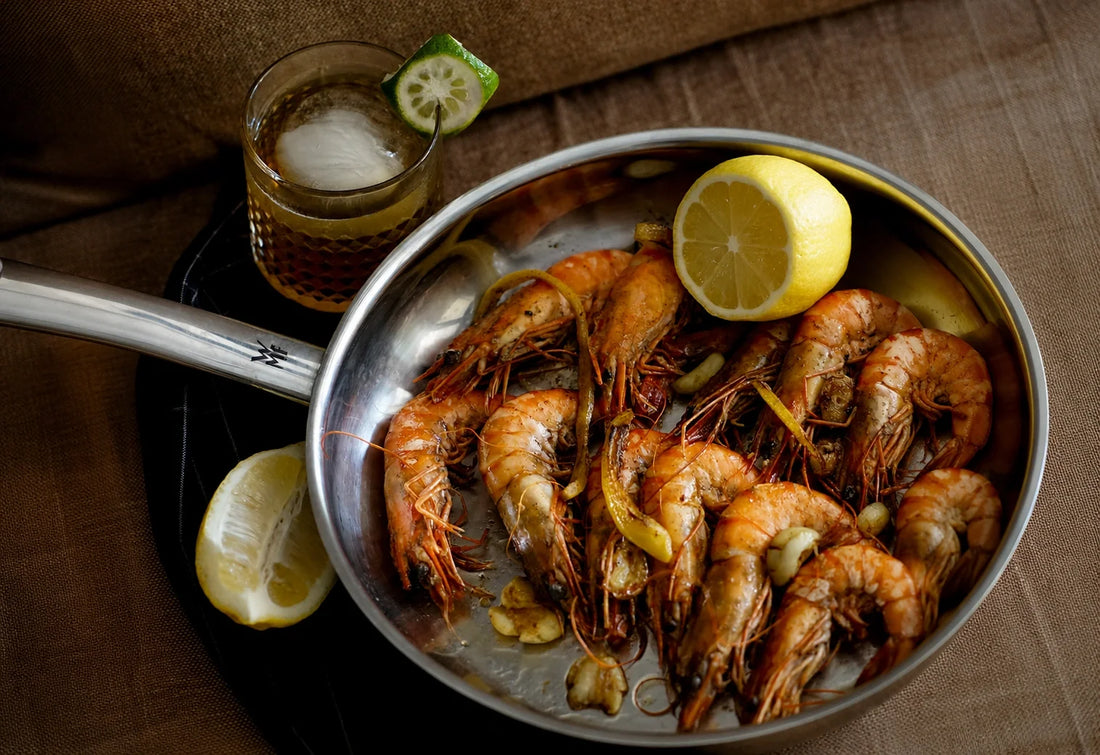 Pan-seared prawns with lemon and garlic served alongside a Melati Drinks botanical cocktail.