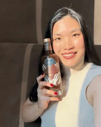 Lorin holding a bottle of Melati and raising a glass